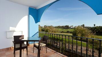 Un balcón con una mesa y sillas, con vistas a un campo de golf.