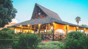 A building with a thatched roof, a covered outdoor area with seating, and a staircase leading up to the entrance. - Playaballena Hotel (Rota)