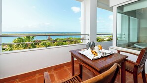 Un balcón con una mesa lista para el desayuno, con vistas a un paisaje costero.