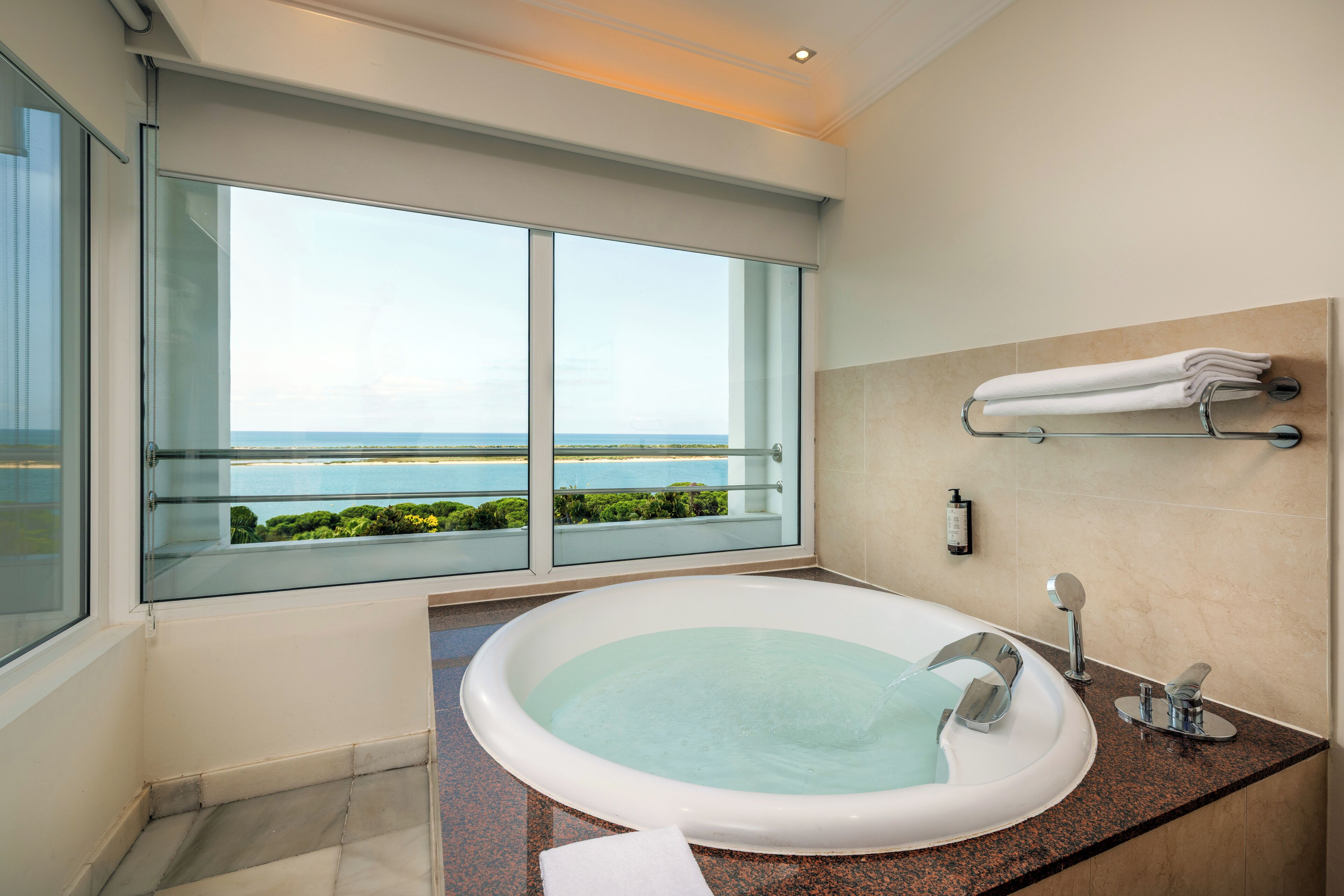 Un baño moderno con una bañera grande, una ducha con cerramiento de vidrio y vistas al océano.