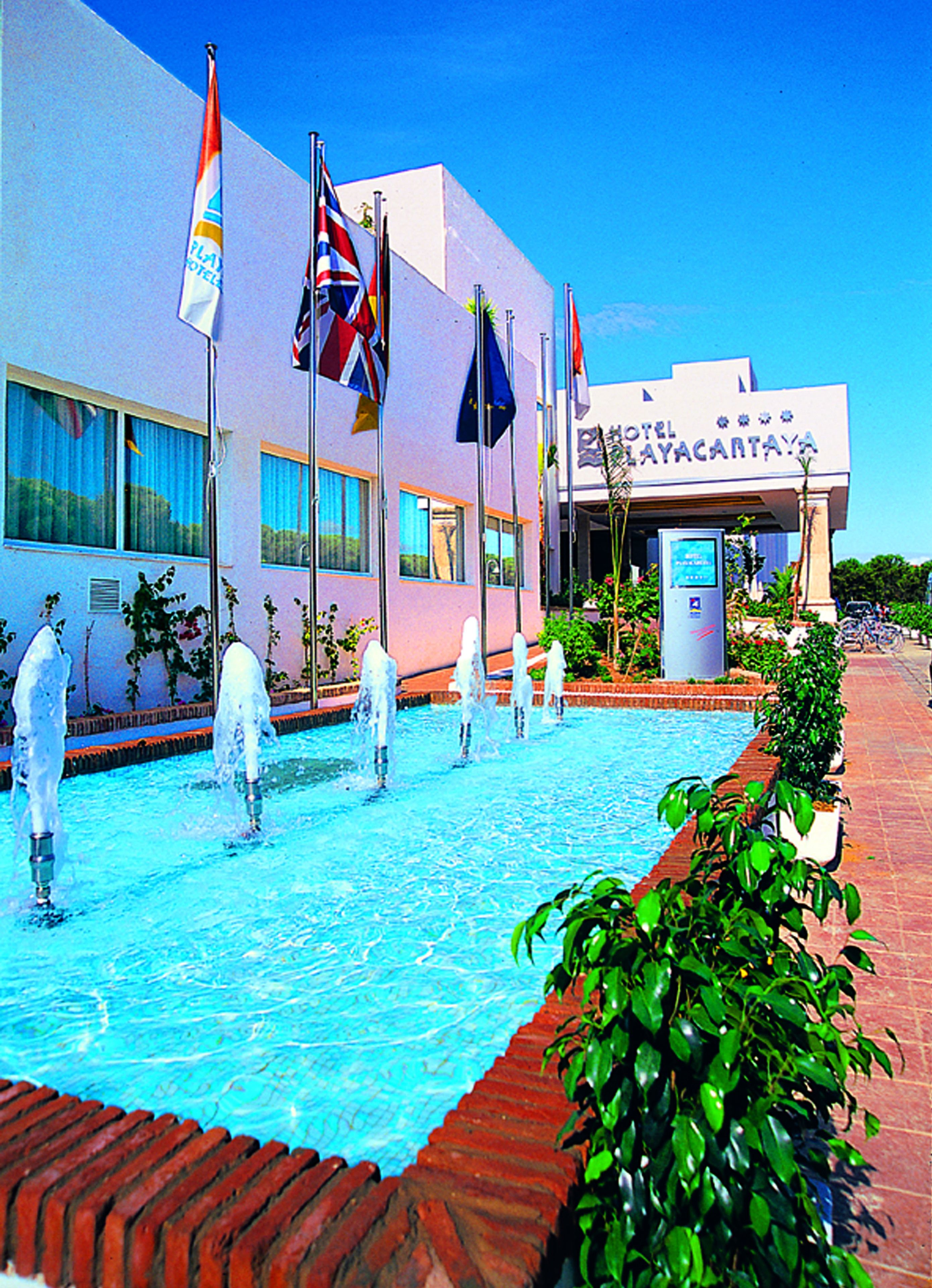 Un hotel con piscina, varias banderas y un letrero que dice "HOTEL MAYACARTAVA".