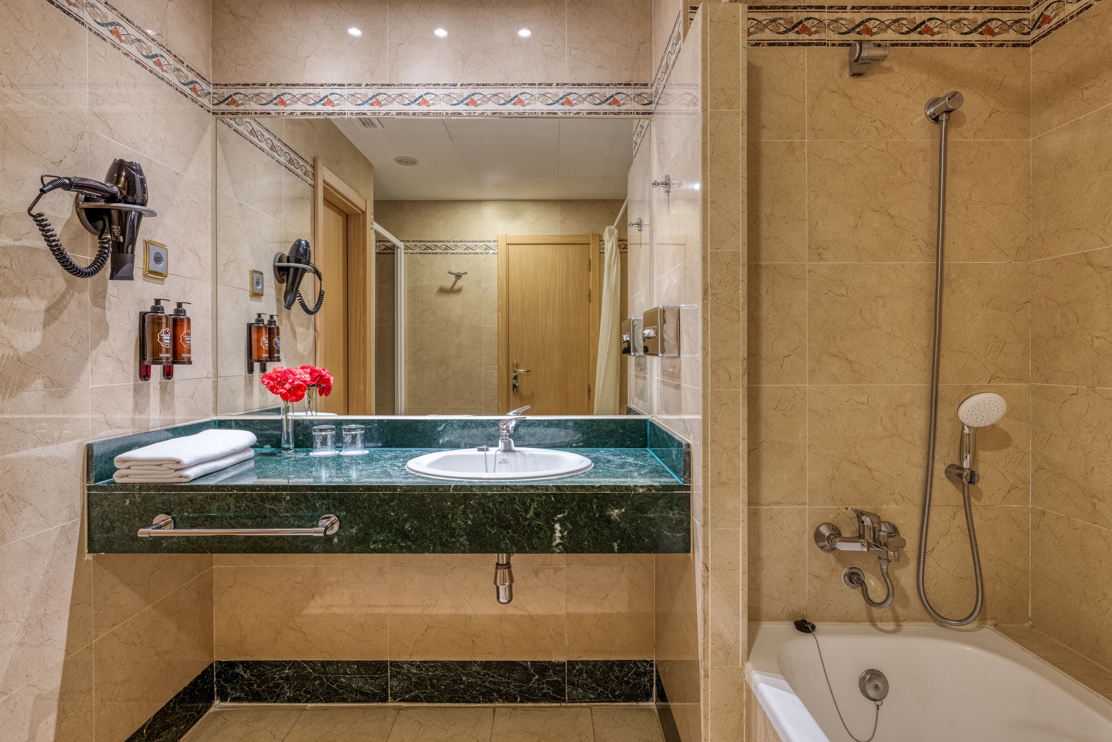 Un baño con lavamanos de mármol, ducha y perchero para toallas.