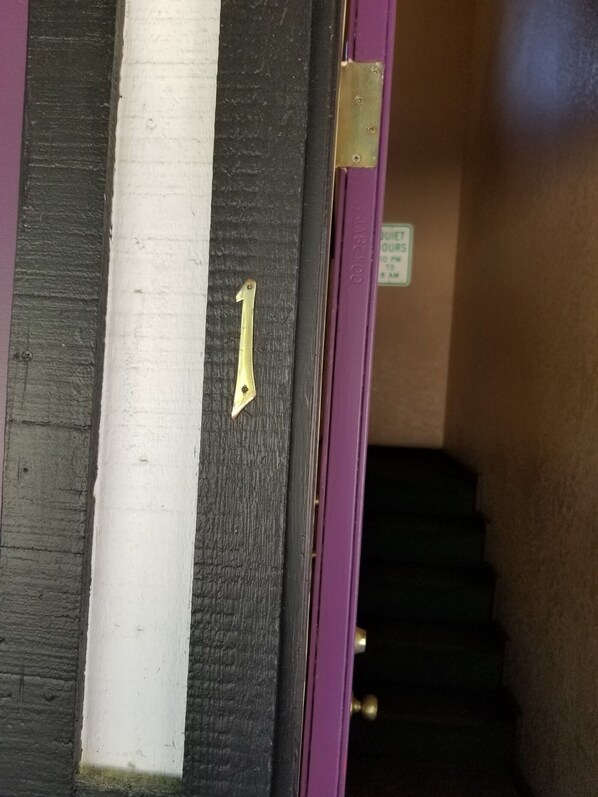 En dörr med ett mässingshandtag, en vit vertikal rand och en lila ram.