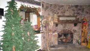 A stone-walled room with a fireplace, a Christmas tree, and various decorations. - Timberline Lodge (Big Bear Lake)