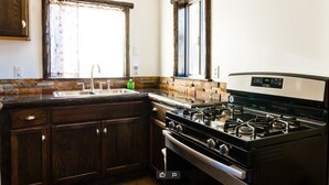 A kitchen with dark wooden cabinets, a gas stove, and a sink. - Timberline Lodge (Big Bear Lake)