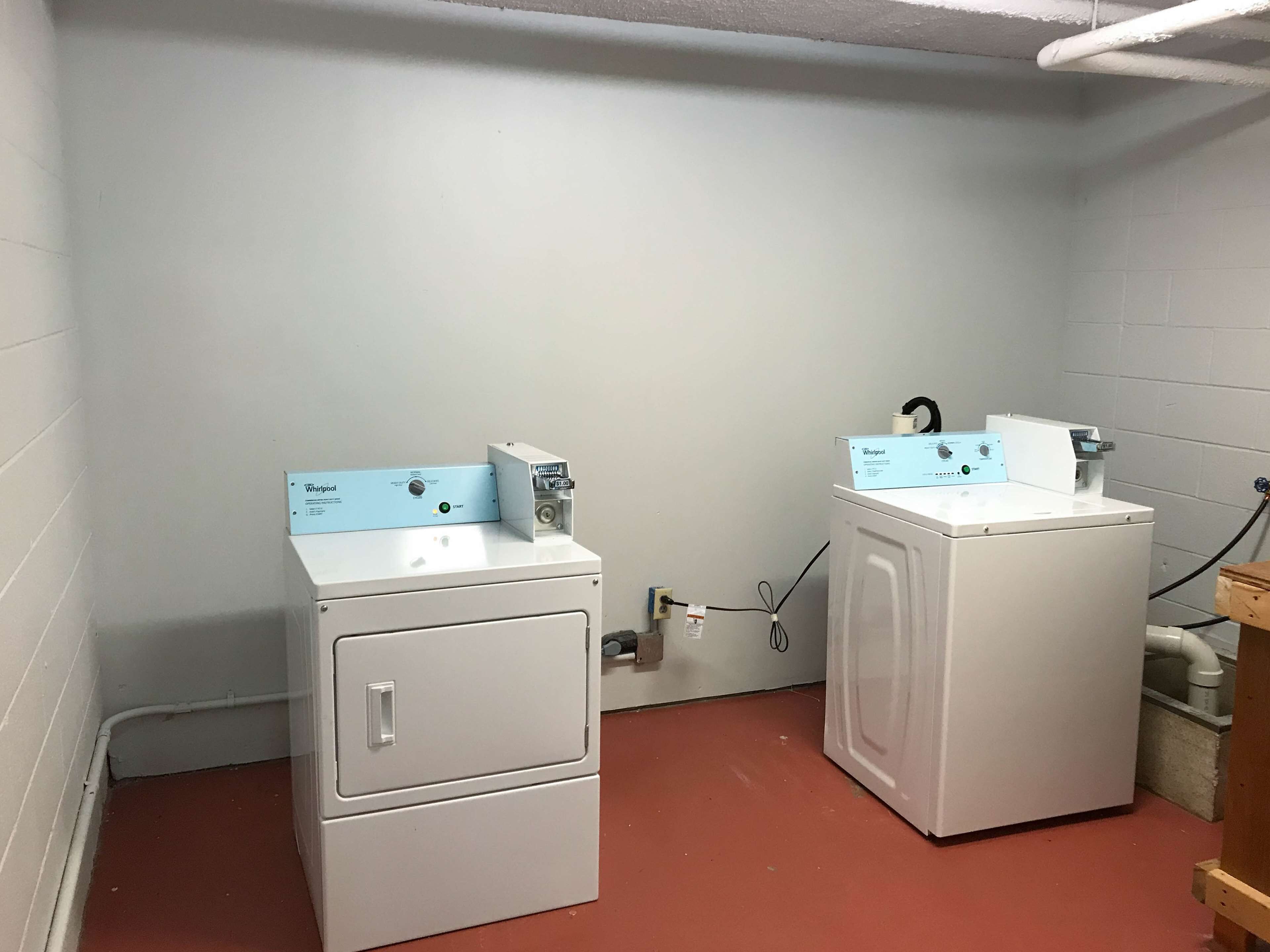 A laundry room with two white washing machines and a blue Whirlpool dryer.