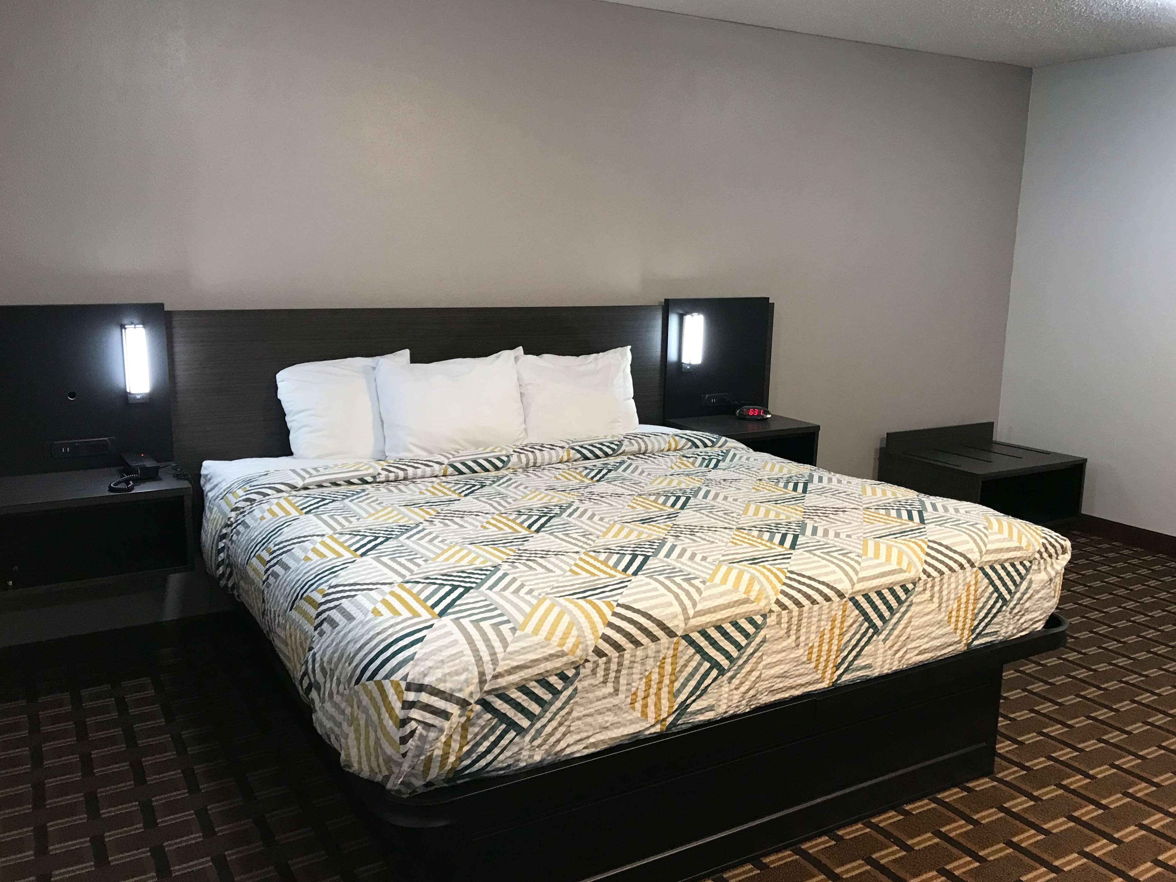 Una habitación de hotel con una cama, dos mesitas de noche y un televisor de pared.