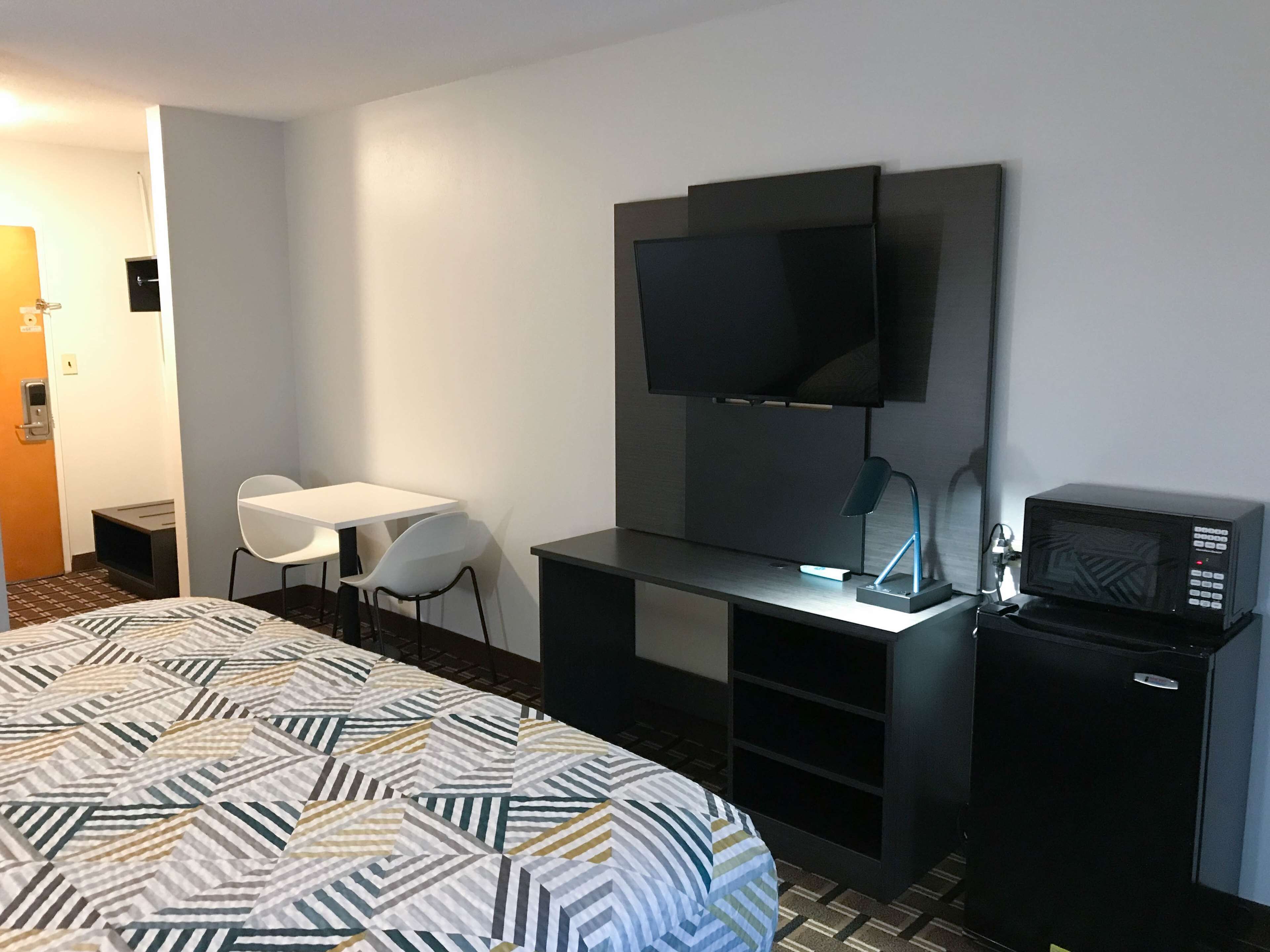 A hotel room with a bed, a desk, a TV, and a microwave.