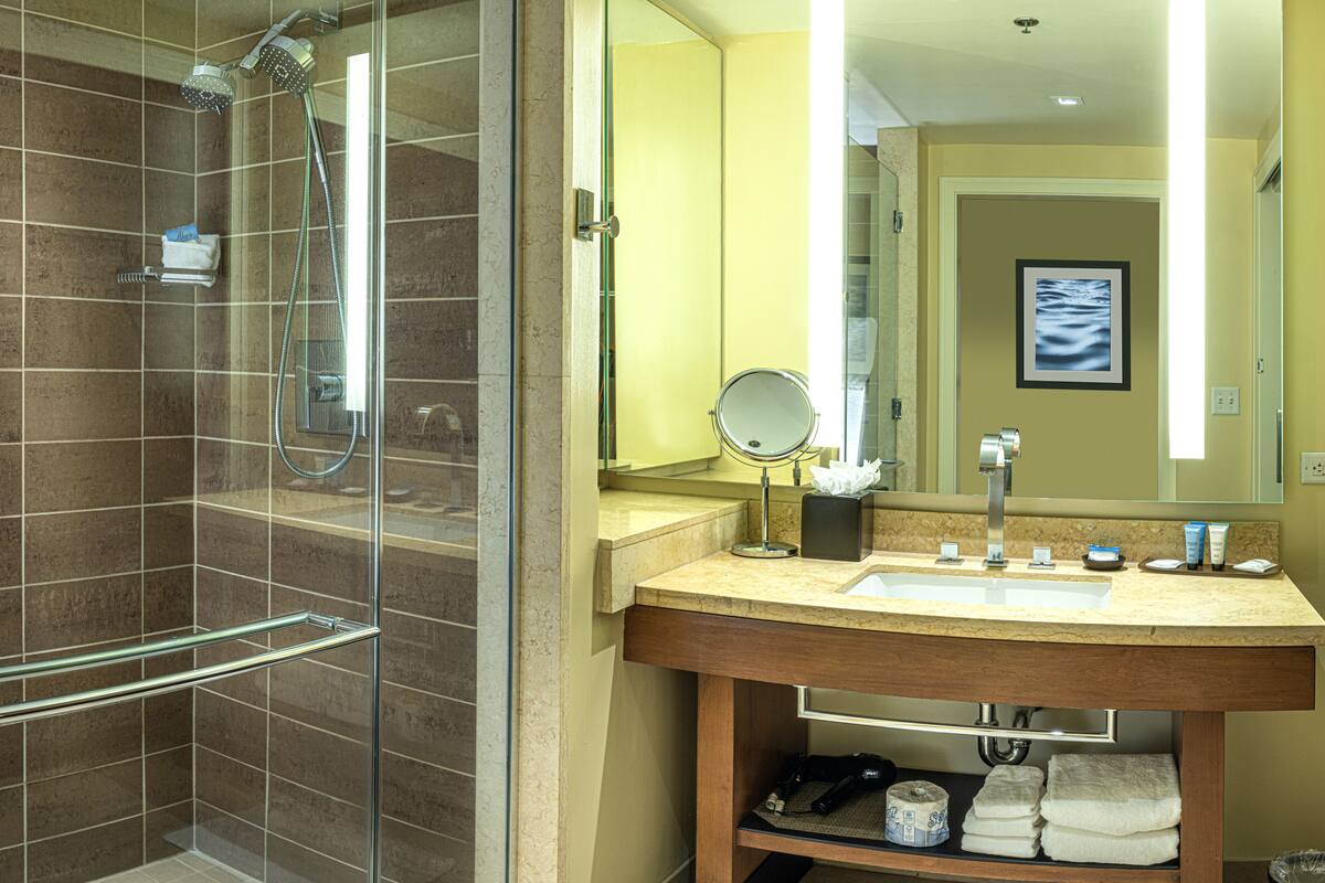 A modern bathroom with a glass-enclosed shower, a vanity with a sink, and a large mirror.