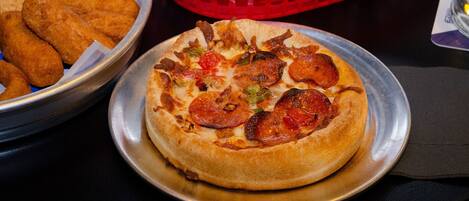 A pizza with pepperoni and vegetables on a metal plate.