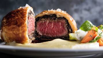 A steak with a crust, served with vegetables and a side of sauce.