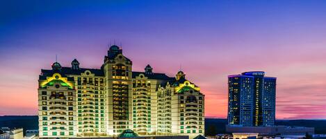 A hotel with multiple floors, a prominent dome structure, and a parking area with cars.