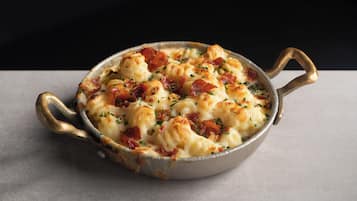Un piatto in padella con manici, contenente formaggio e pancetta.