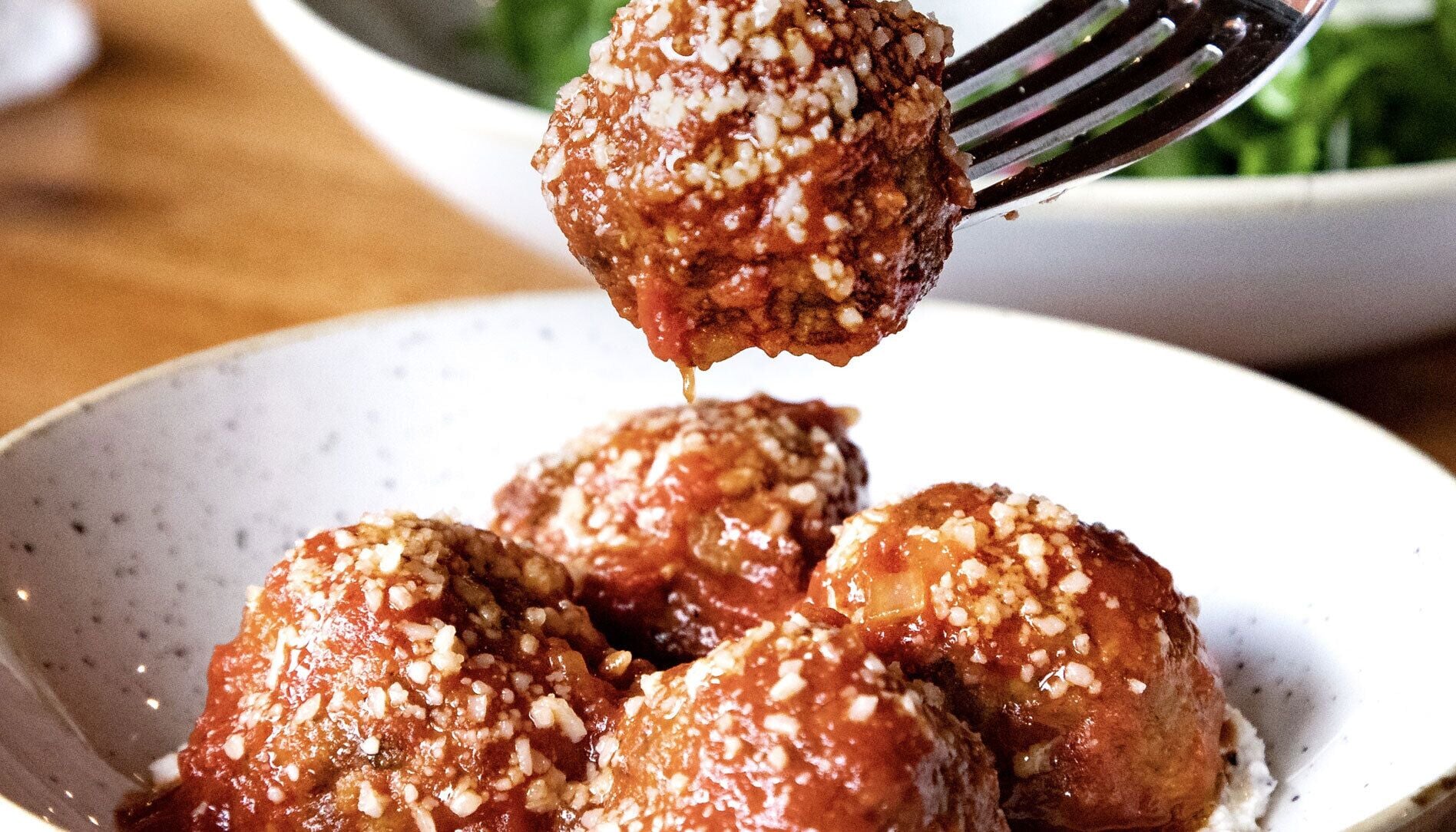 A bowl of meatballs topped with sesame seeds.