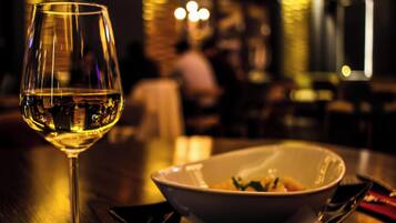 Una copa de vino blanco sobre una mesa con un bol de comida y cubiertos.