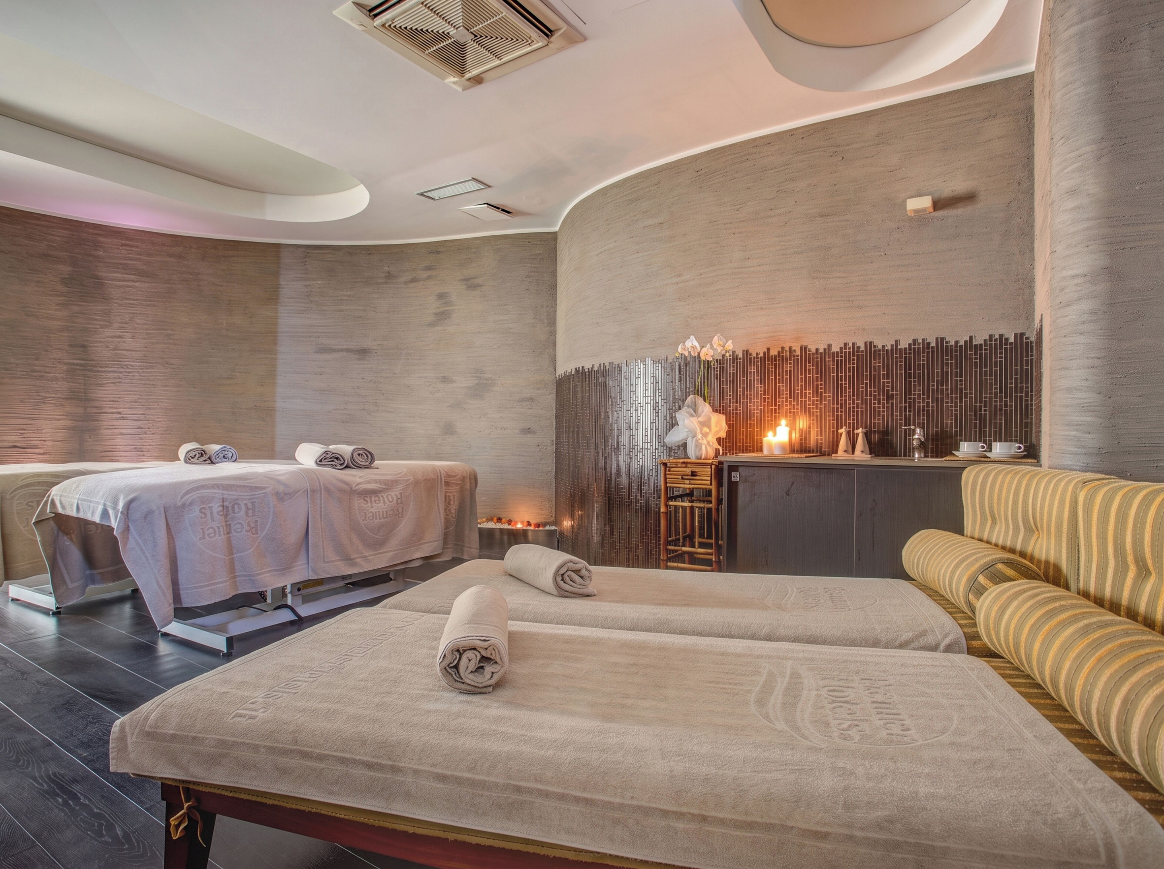 Un cuarto de spa con dos camillas de masaje, un mostrador de recepción y una zona de estar.