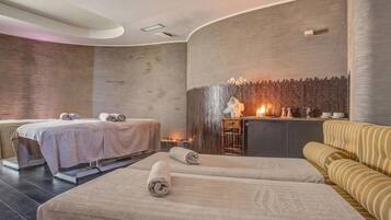 Un cuarto de spa con dos camillas de masaje, un mostrador de recepción y una zona de estar.