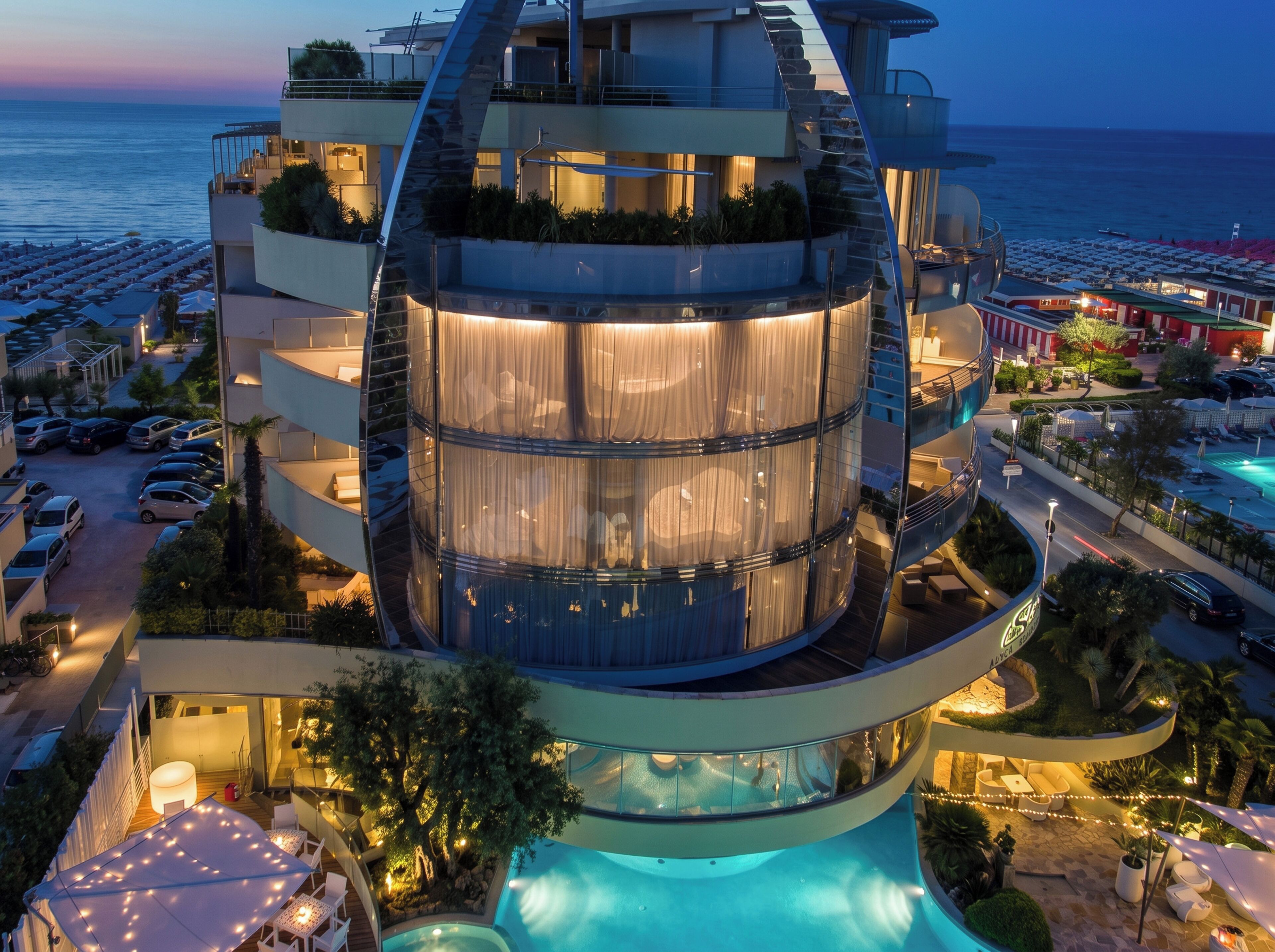 A modern hotel with a circular atrium, outdoor pool, and a view of the sea.