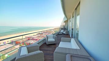 Enjoy the ocean view from this balcony with wicker furniture and a glass railing.
