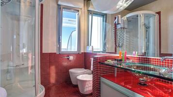 Un baño moderno con ducha envuelta en vidrio, inodoro y tocador con lavamanos de vidrio.
