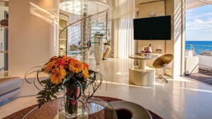 A modern interior with a glass staircase, a flat-screen TV, and a view of the sea. - Hotel Waldorf - Premier Resort (Cervia)