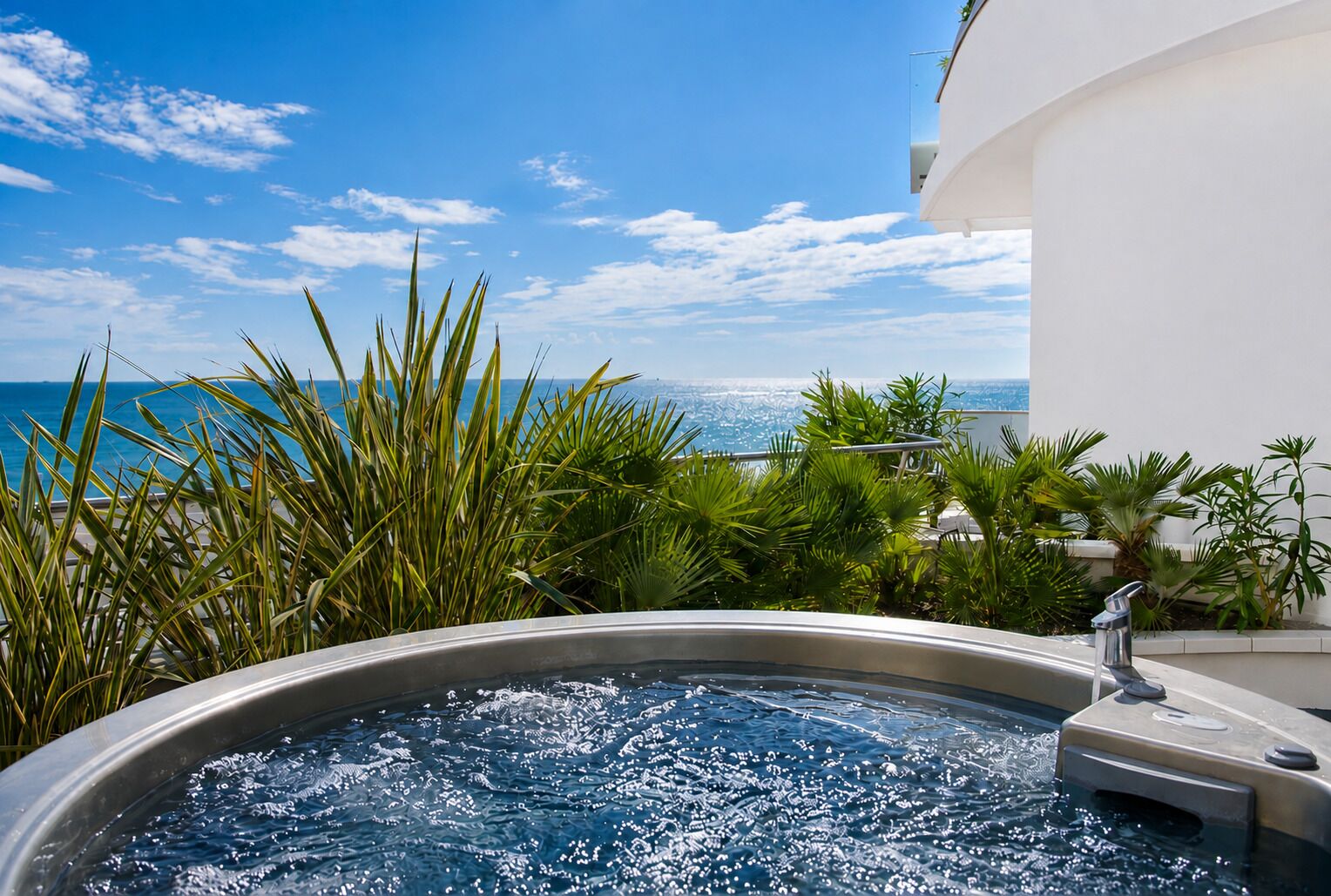 A hot tub with a view of the ocean, surrounded by tropical plants.