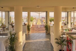 A hotel corridor with a view of a beach and cityscape.