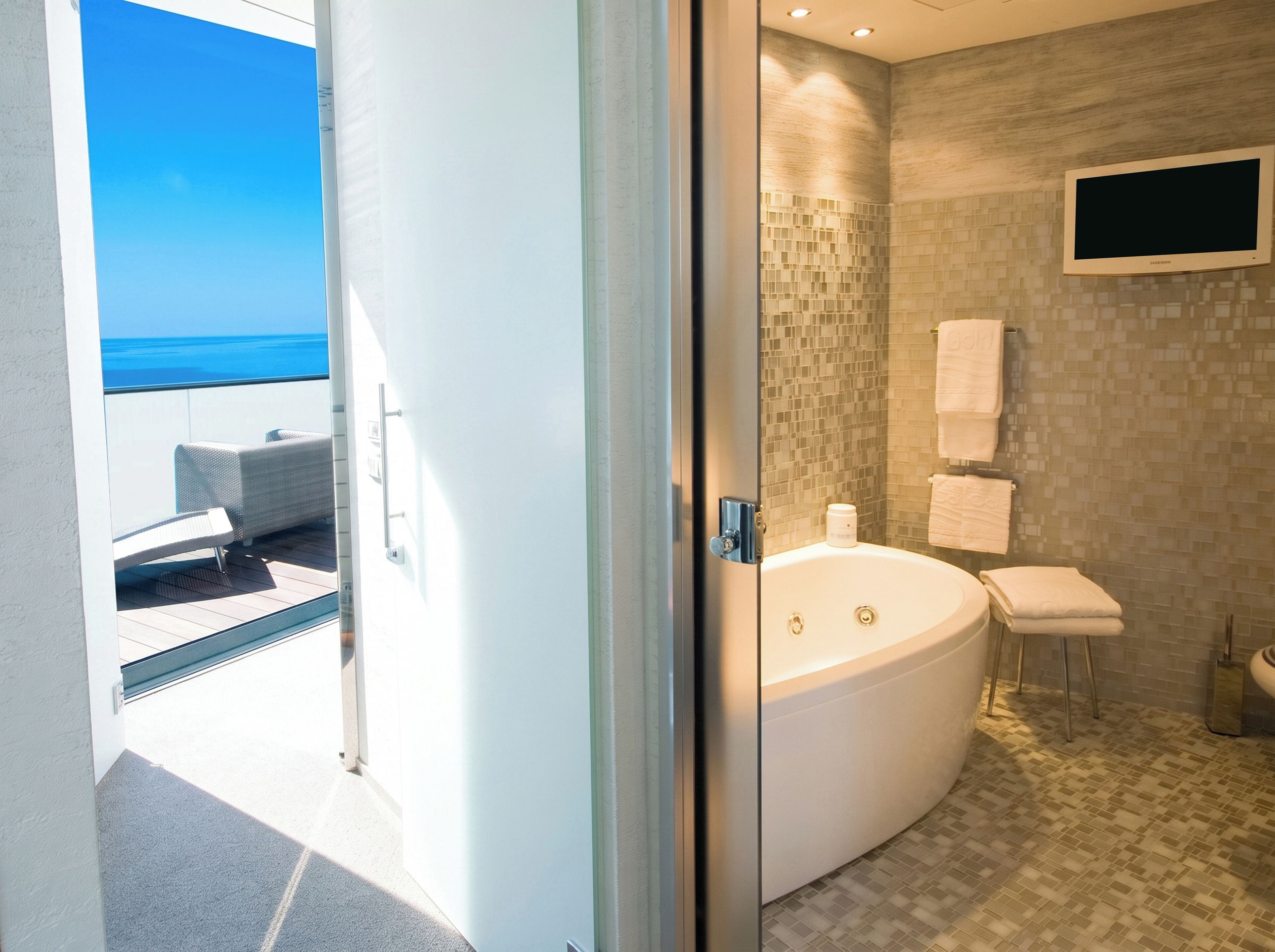 Une salle de bain moderne dotée d’une grande baignoire, d’une douche à parois de verre et offrant une vue sur l’océan.