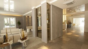 A spacious lobby with a reception desk, seating area, and a large window providing natural light. - Hotel Carillon (Cervia)