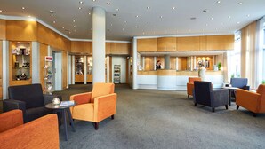 A reception area with a reception desk, seating area with chairs, and a counter with a sign that reads "RECEPTION". - Atlantic Hotel Vegesack (Bremen)