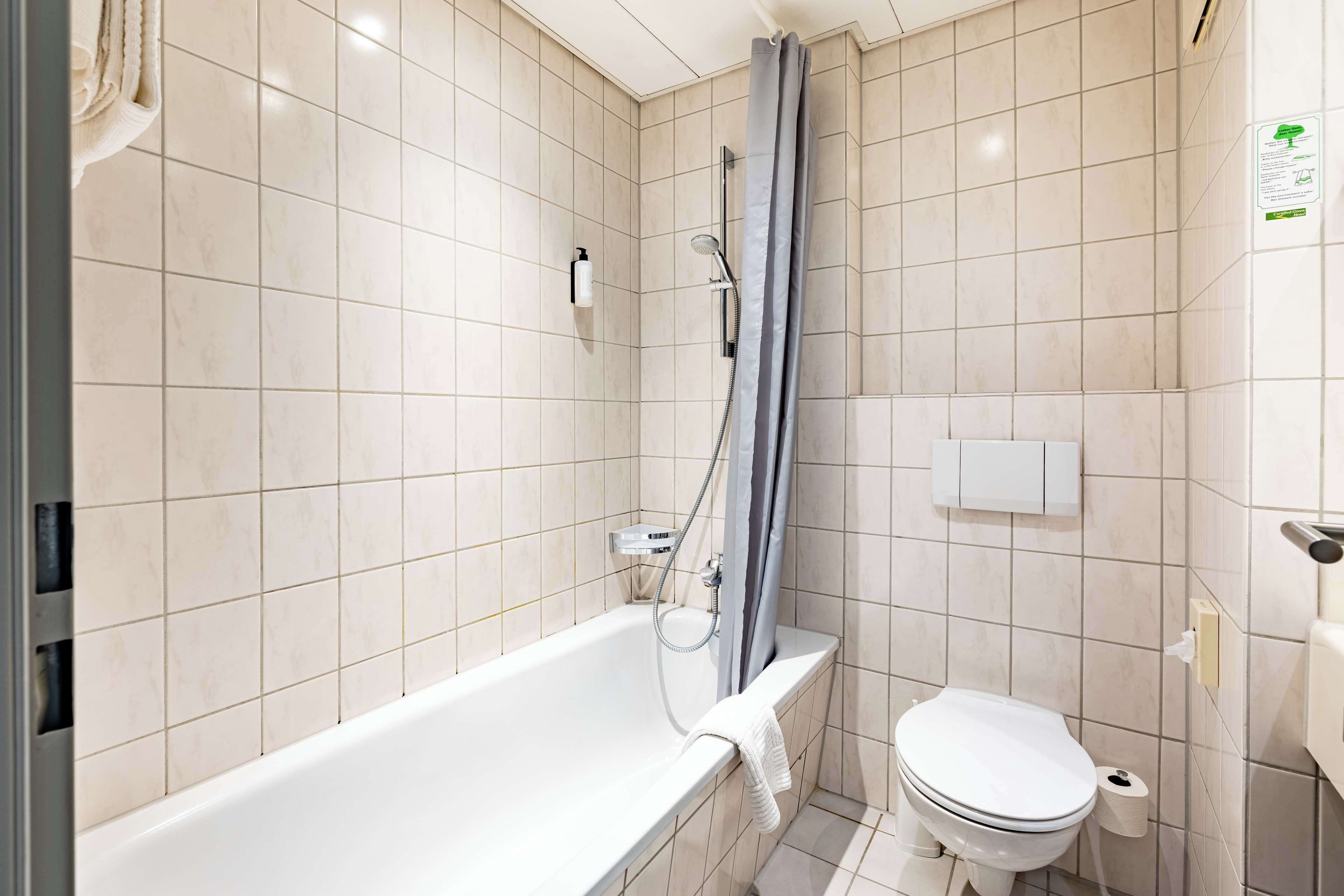 Un baño con bañera, inodoro y cortina de ducha.