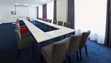 A conference room with a long table, chairs, a projector screen, and a whiteboard.