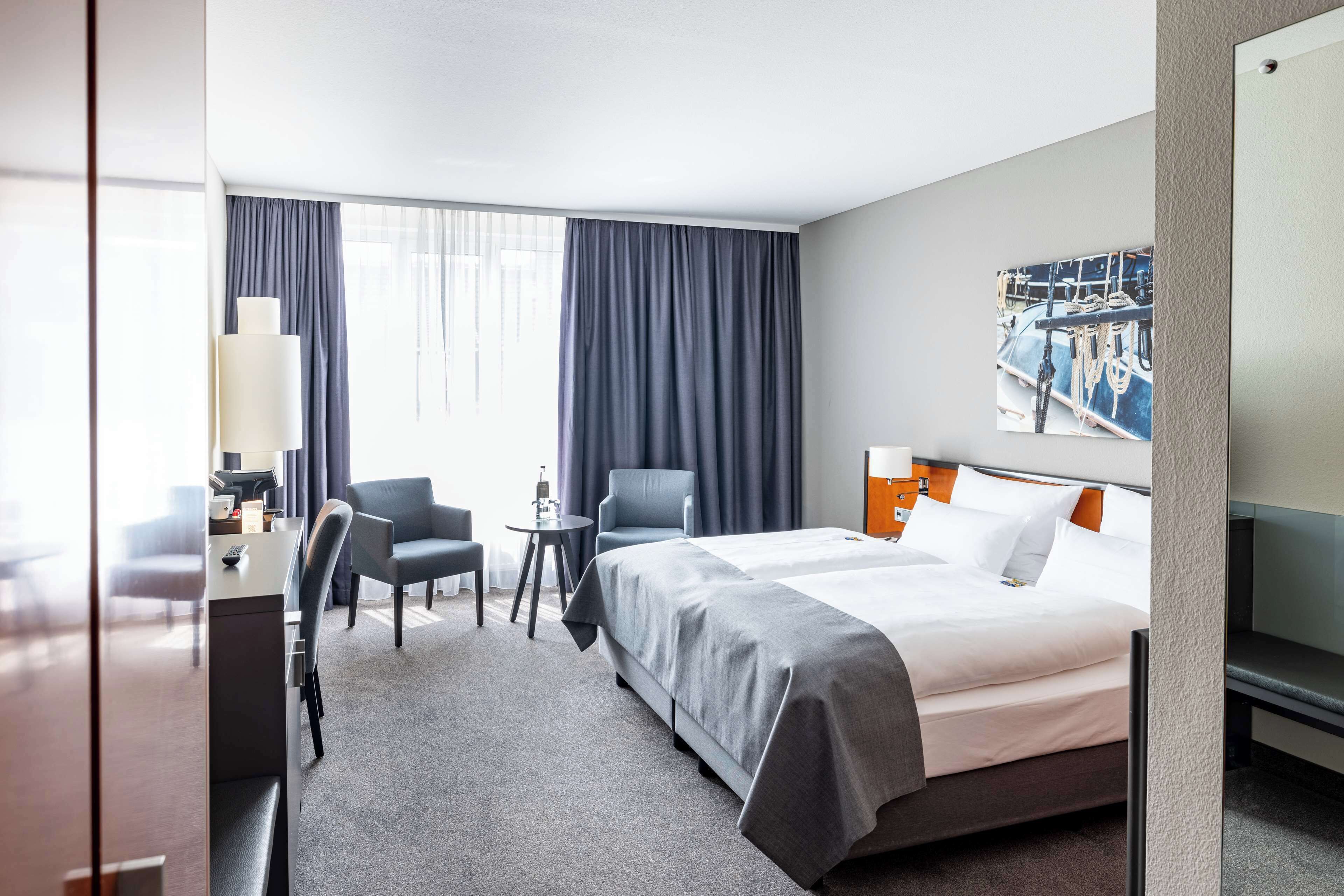 Una habitación de hotel con cama, dos sillas, un escritorio y una mesita.