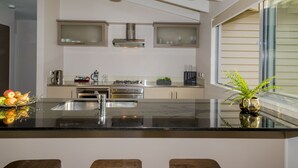 A modern kitchen with a black countertop, stainless steel appliances, and a large window. - Arrowfield Apartments (Arrowtown)