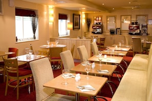 A restaurant with multiple tables and chairs, a bar area, and a coffee machine. - Premier Inn Heathrow Airport - M4/J4 (Hayes)
