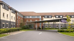 A hotel entrance with a covered walkway, a parking lot, and a sign for the Premier Inn. - Premier Inn Heathrow Airport - M4/J4 (Hayes)