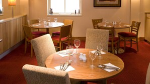 A dining area with round tables, chairs, and empty wine glasses. - Premier Inn Heathrow Airport - M4/J4 (Hayes)