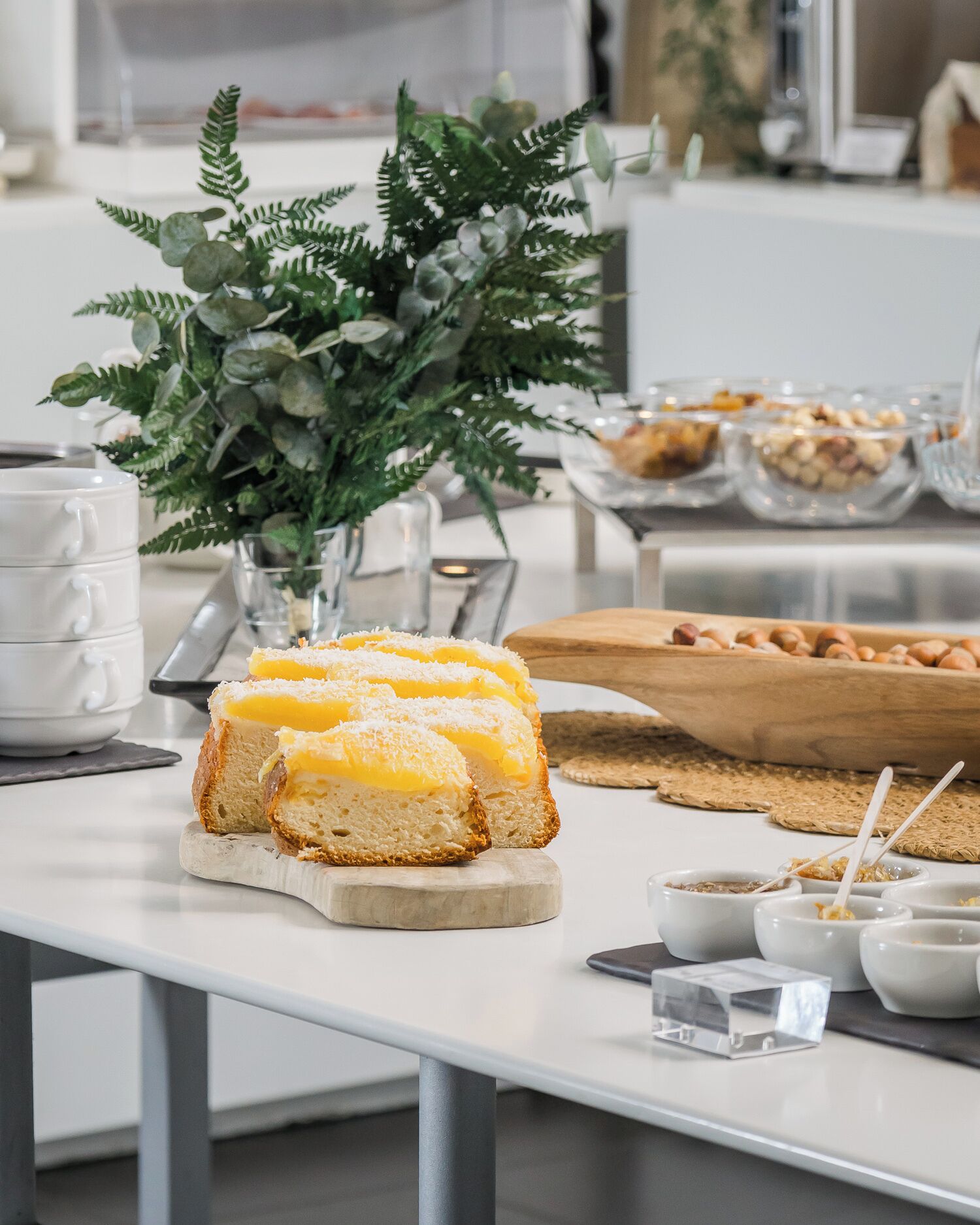 Une table de buffet proposant une variété de plats, notamment un pain avec du beurre, des bols de condiments et une plante décorative.