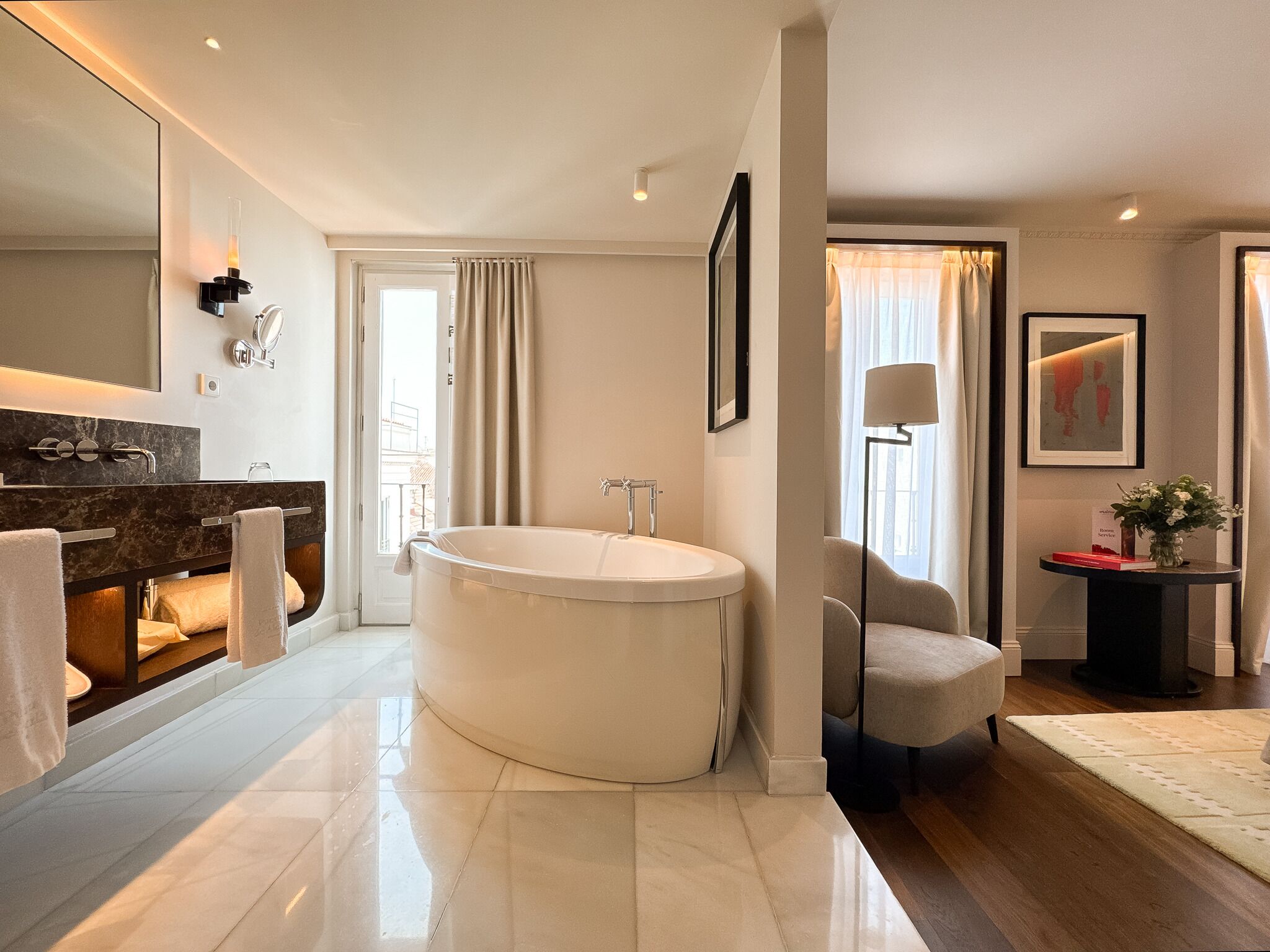 A modern bathroom with a large bathtub, a vanity with a mirror, and a chair.