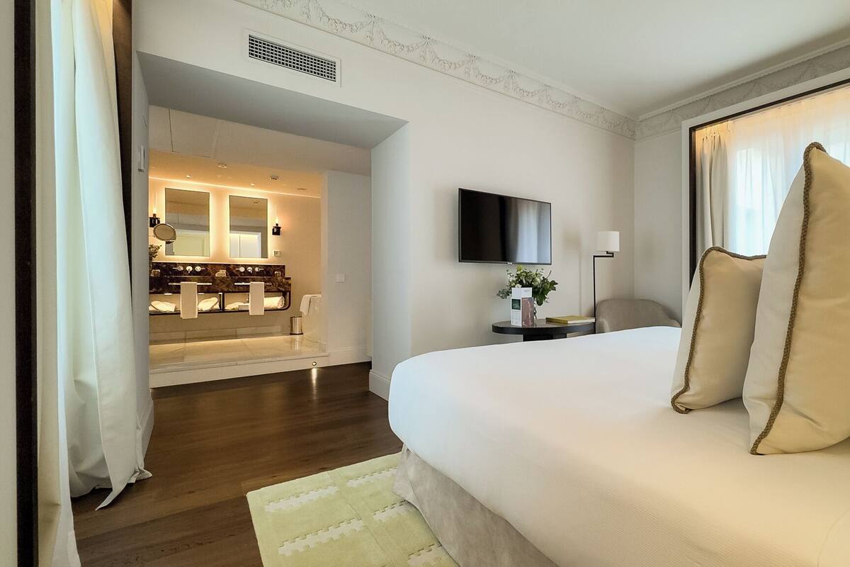 Hotelkamer met een groot bed, een televisie, een nachtkastje en een badkamer zichtbaar door een geopende deur.