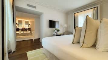 A hotel room with a large bed, a TV, a bedside table, and a bathroom visible through an open door.