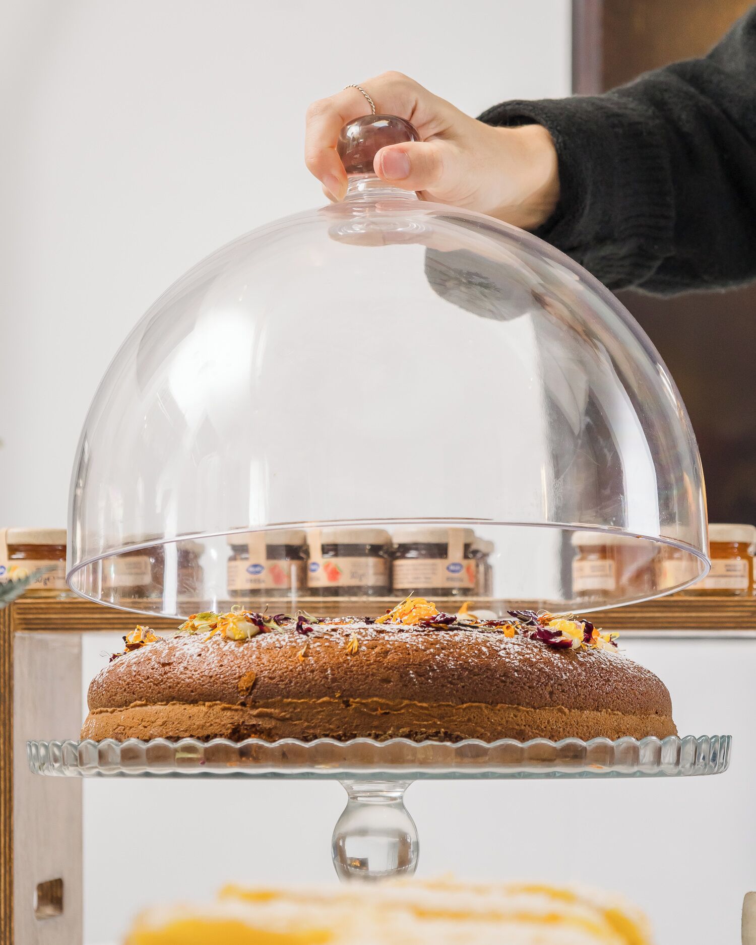 A cake on a glass cake stand with a glass dome cover.