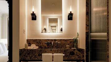 A bathroom with a granite countertop, two sinks, a large mirror, and two wall-mounted lights.