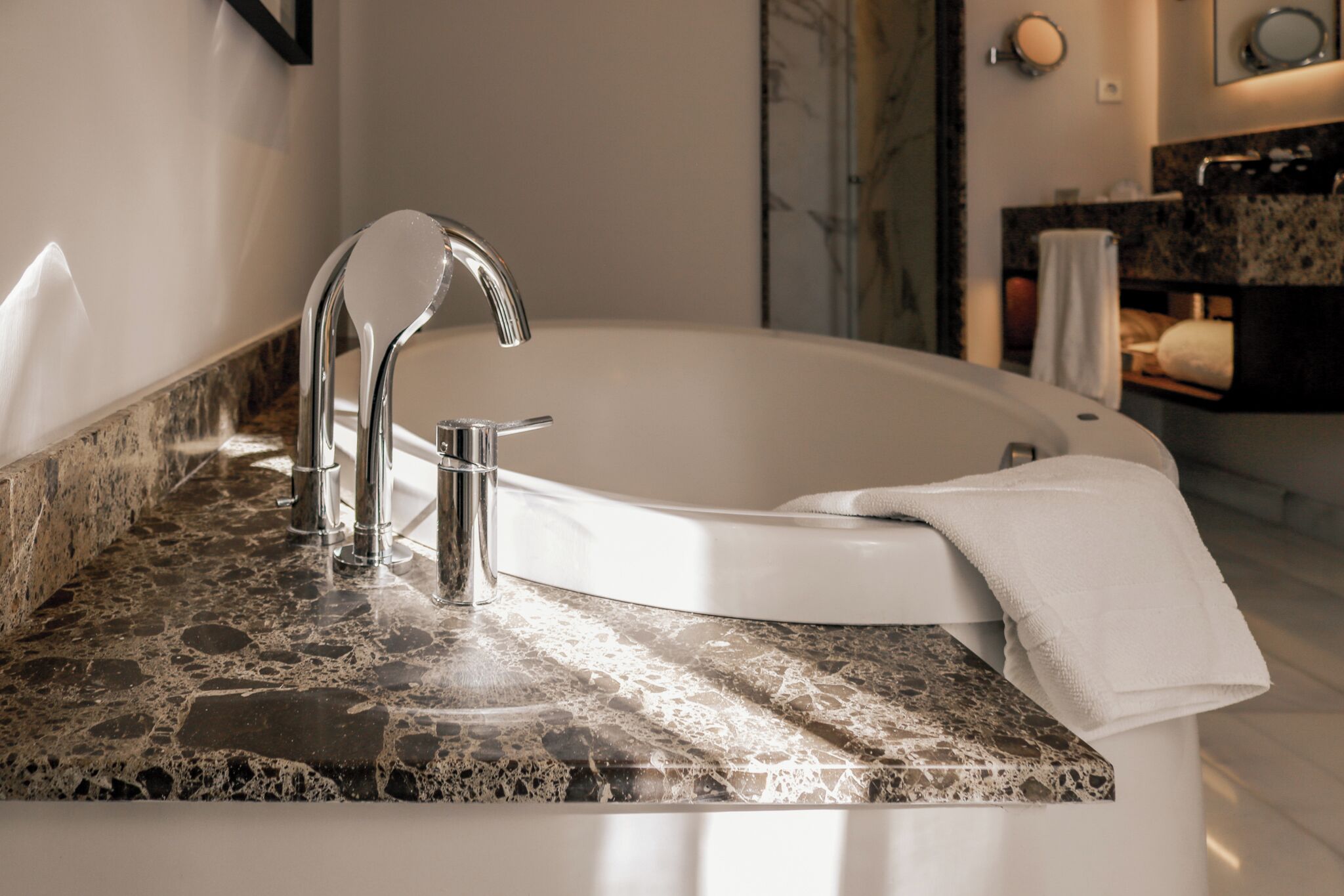 A modern bathroom with a freestanding bathtub, a marble countertop, and a towel on the edge.