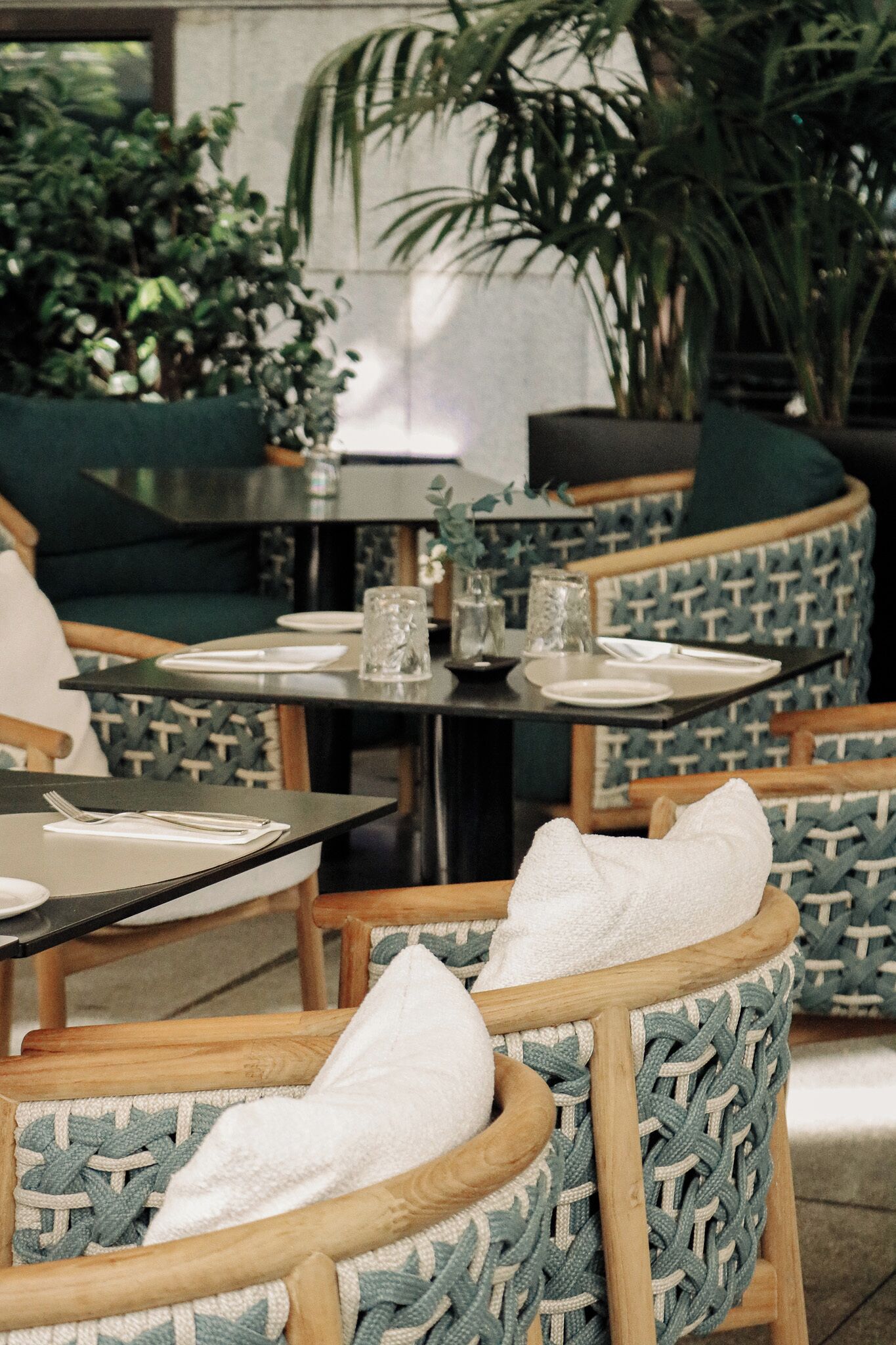 An outdoor seating area with round tables and chairs, some with cushions.