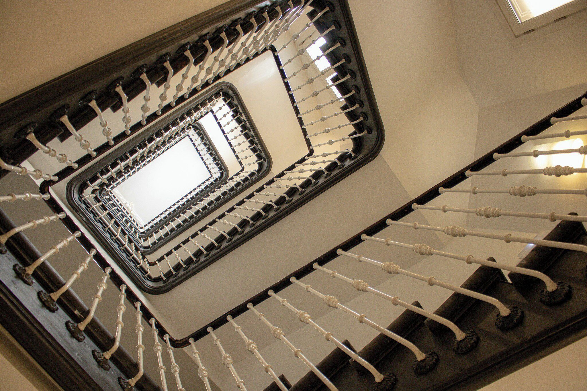 Uma escadaria em espiral com um vão central aberto e piso refletivo.