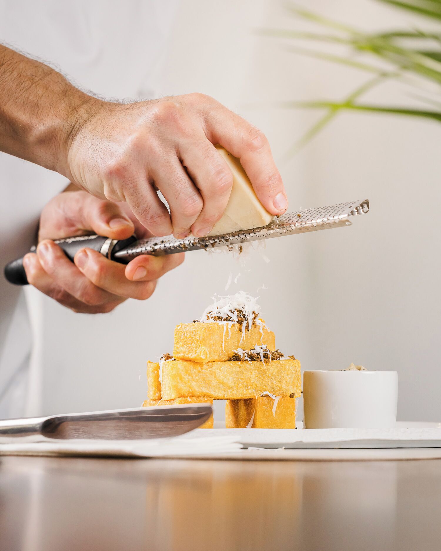 A person grating cheese over a stack of bread.