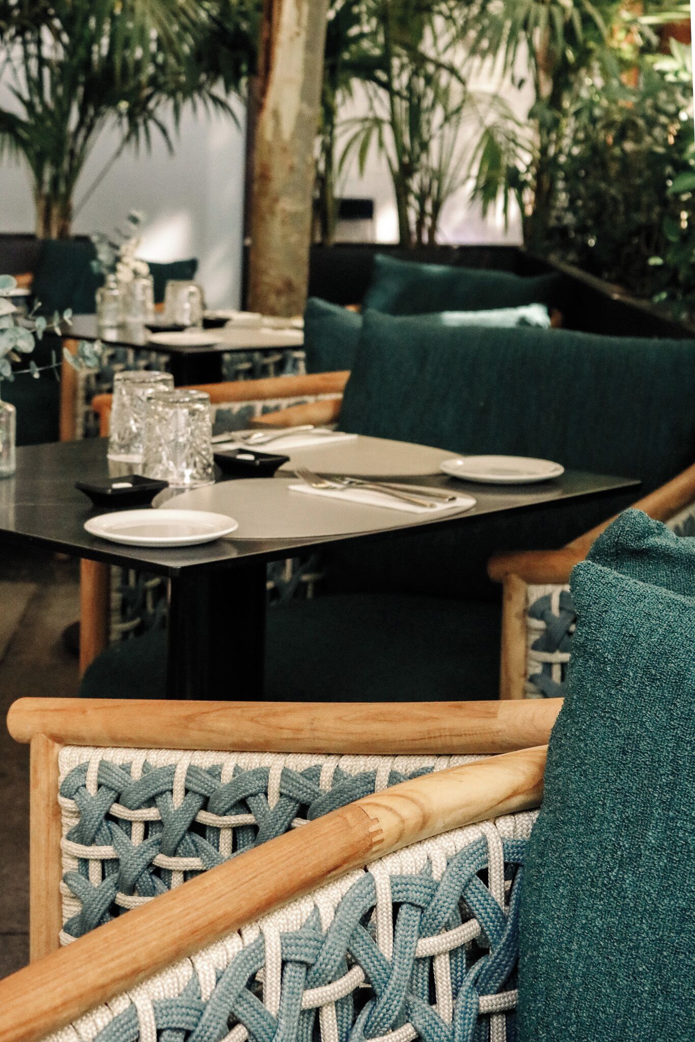 A dining area with tables set for two, chairs with patterned cushions, and a green upholstered sofa.