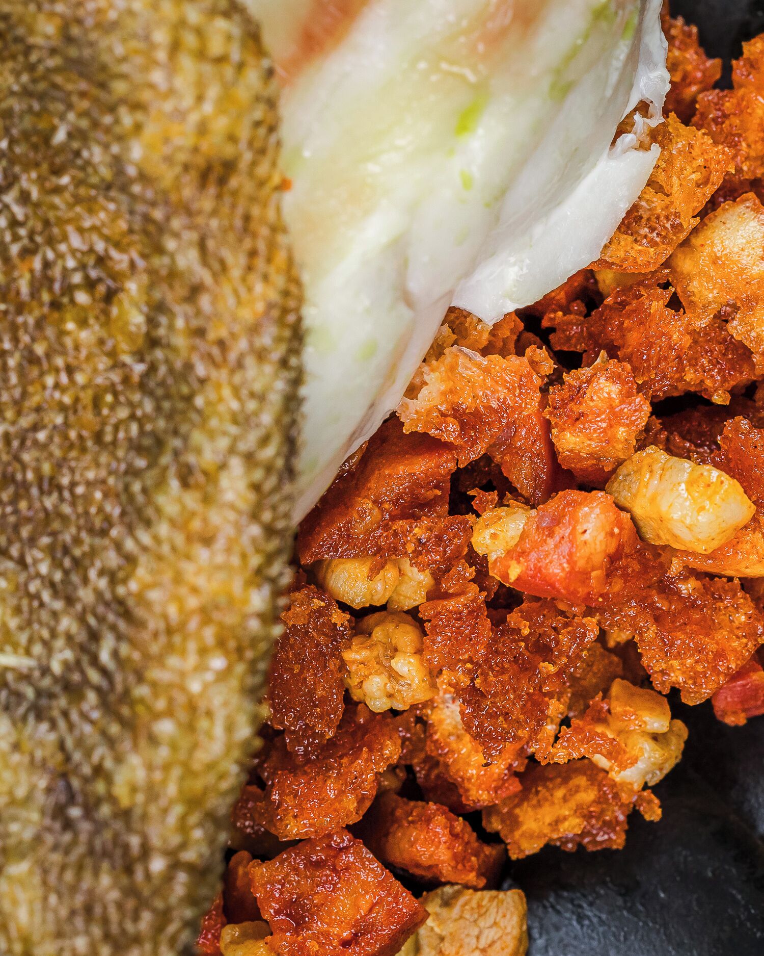 A close-up of a dish with crispy fried food and a white sauce.