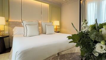 A hotel room with a large bed, two bedside lamps, a nightstand, and a potted plant.